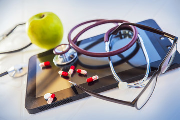 green Apple, medical stethoscope and pill tablet, still life on the theme of diet