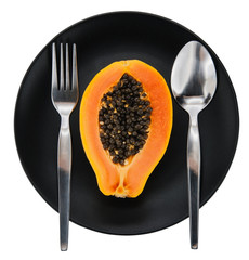Papaya on white plate, black background.