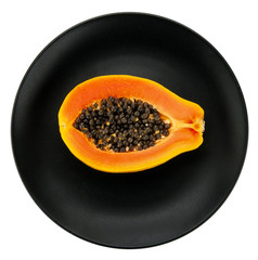 Papaya on white plate, black background.