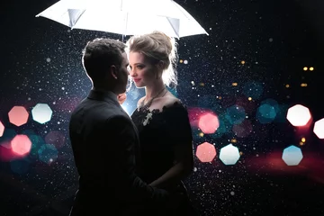 Foto op Plexiglas Beautiful couple man with woman with white umbrella in flash lights and rain drops   © Oleksandr Kozak