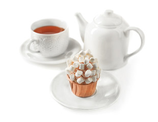 Cup of tea with tasty cupcake and teapot, isolated on white