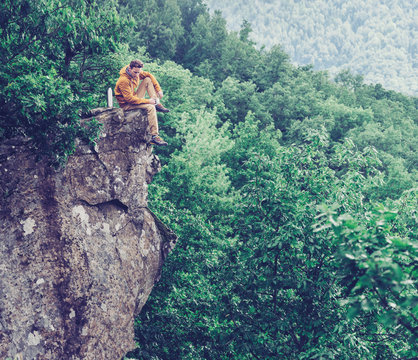 Traveler sitting on top of cliff and drinking tea