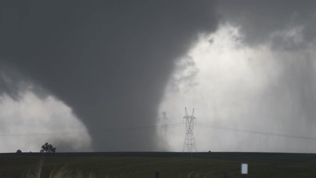 A massive wedge-shaped tornado advances toward the camera over Nebraska farmland