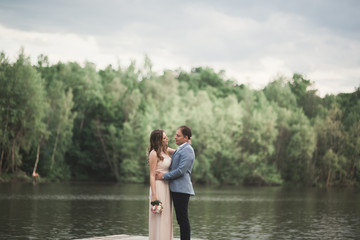 Charming bride, elegant groom on landscapes of mountains and sunset at lake. Gorgeous wedding couple