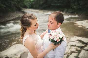 Bride and groom holding beautiful wedding bouquet. Lake, forest