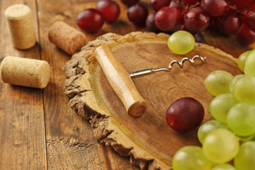 Wine corks and tailspin with bunch of grapes on wooden background