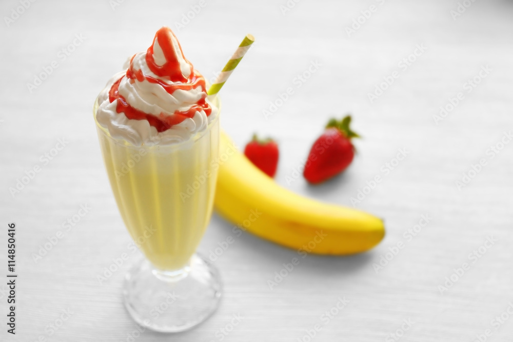 Fototapete Delicious milkshake with strawberry and banana on wooden table