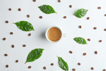 Cup of tasty coffee with leaves on white background