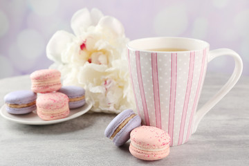 Cup of tea with macaroons and peonies on wooden table