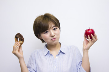 リンゴとドーナッツを持つ若い女性