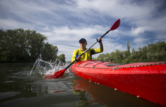 A Man Paddles A Red Kayak.