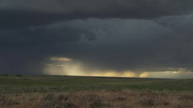 Updraft base with cloud to ground strokes dumping rain over prairie and accompanied by lightning, time lapse