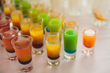 View of alcohol setting on catering banquet table, row line of different colored alcohol cocktails on a party, martini, vodka, and others on decorated catering bouquet table event
