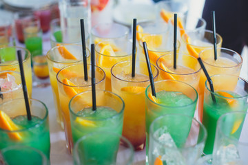 View of alcohol setting on catering banquet table, row line of different colored alcohol cocktails on a party, martini, vodka, and others on decorated catering bouquet table event