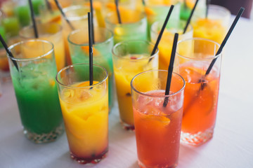 View of alcohol setting on catering banquet table, row line of different colored alcohol cocktails on a party, martini, vodka, and others on decorated catering bouquet table event