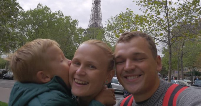 Happy family of mother, father and little son making selfie video against the Eiffel Tower. Visiting Paris, France