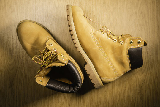 Pair of old yellow working boots Isolated on wood background