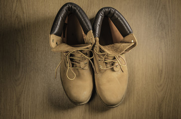 Pair of old yellow working boots Isolated on wood background