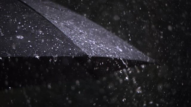 Close-up ultra-slow motion rain falling on a black umbrella
