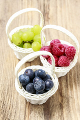 Baskets with fruits: raspberry, blueberry and grapes.