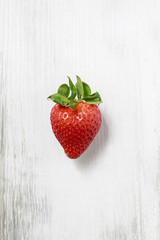 Single strawberry on wooden background