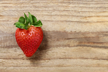 Single strawberry on wooden background
