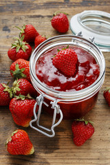Jar of strawberry jam on wooden table