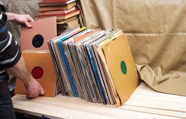 Retro styled image of a collection of old vinyl record lp's with sleeves on a wooden background. Browsing through vinyl records collection. Music background. Copy space