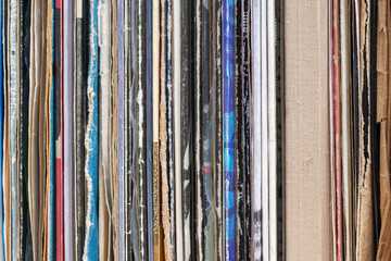 Retro styled image of a collection of old vinyl record lp's with sleeves on a wooden background. Copy space