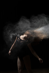 Woman dancing with flour in hair. Black background.