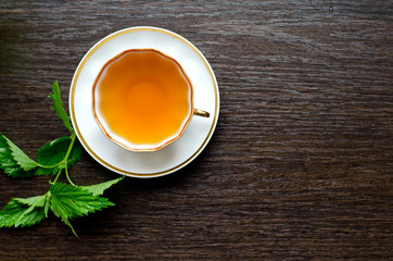 herbal nettle tea in a porcelain Cup on a dark wooden background