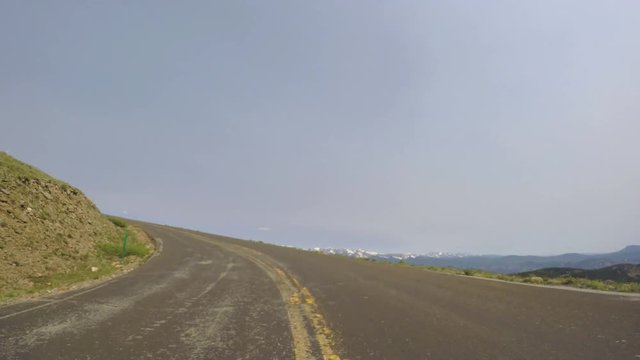 Car driving on paved road above timber line on Mount Evans-POV point of view