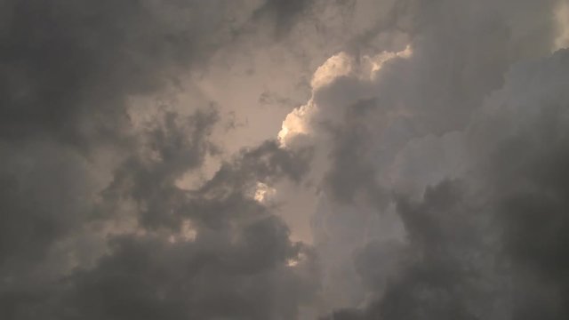 Looking up into a mass of swirling ragged gray clouds in front of billowing sunlit cumulus