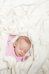 Little cute newborn baby sleeping on its back on a soft blanket.