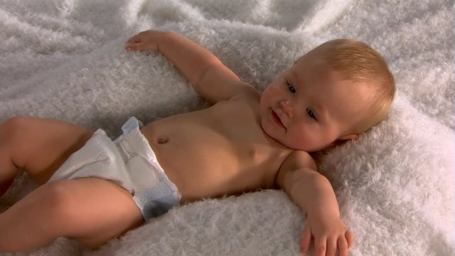Smiling baby in diaper lying on back with outstretched arms