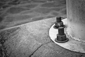 Low section of lighting pole close up of screws and bolts in black and white