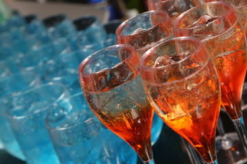Many glasses with an alcoholic drink on a bar counter. 