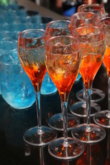 Many glasses with an alcoholic drink on a bar counter. 