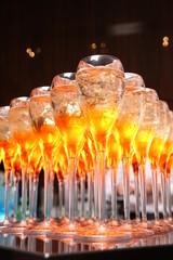 Many glasses with an alcoholic drink on a bar counter. 