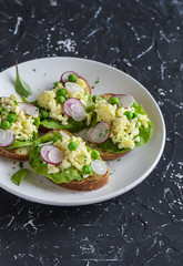 Sandwiches with egg, radish and green peas. On a dark background. Delicious healthy food