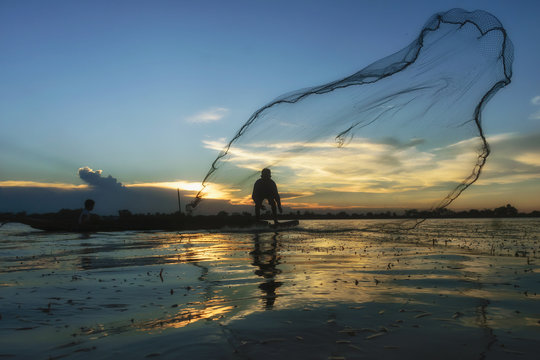 Traditional Asian fishermen throwing net fishing in the river at sunset time.