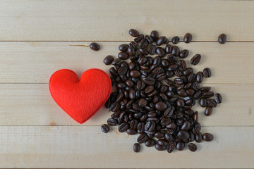 Red heart and coffee beans on a wood floor.