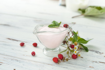 sour cream with wild strawberries on white wooden table
