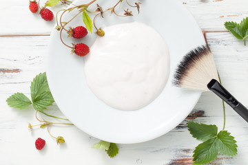 sour cream with wild strawberries on white wooden table