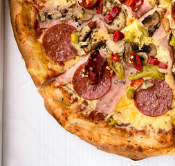 Italian pepperoni pizza with ham, red peppers and cheese