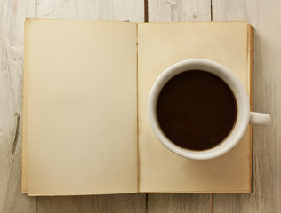 Obraz na płótnie Canvas Cup of dark coffee on page of open old book