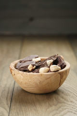 broken homemade bar of chocolate with cashew nuts in wood bowl