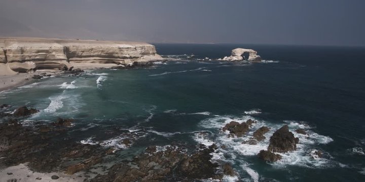 High view of a rugged coast near a bare headland and arched sea stack