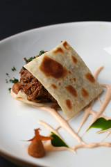 Pieces of pita bread with meat and vegetables on white plate