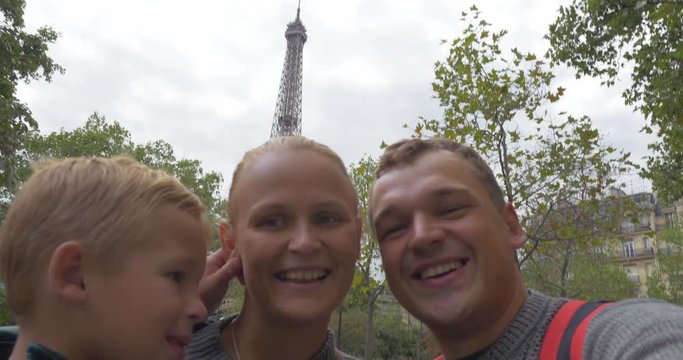 Happy and excited parents with little son shooting selfie on background of Eiffel Tower. Traveling to Paris, France